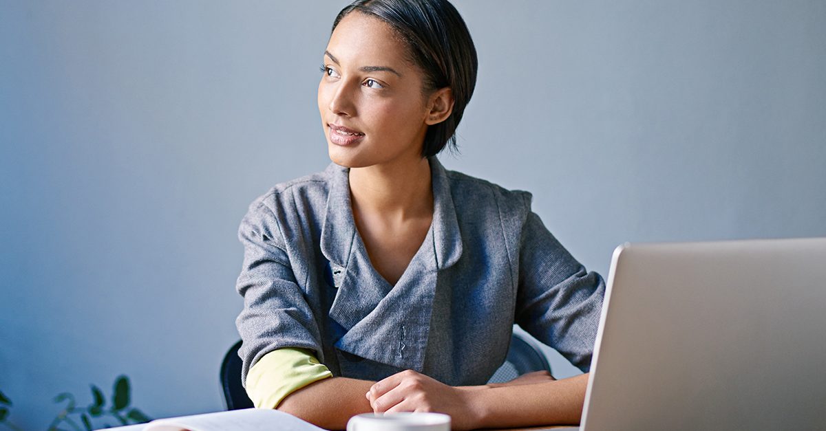 A woman looking to her left with a laptop screen showing in front of her.