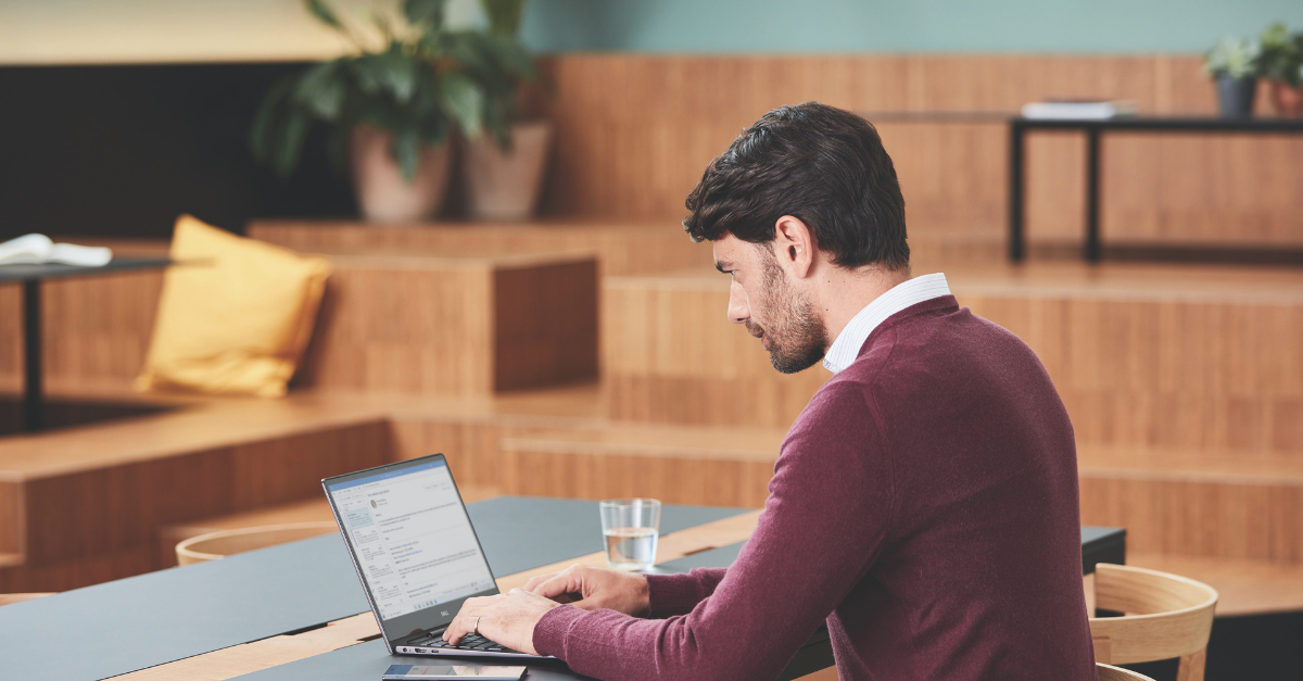 A man working on his laptop with a glass of water near him.