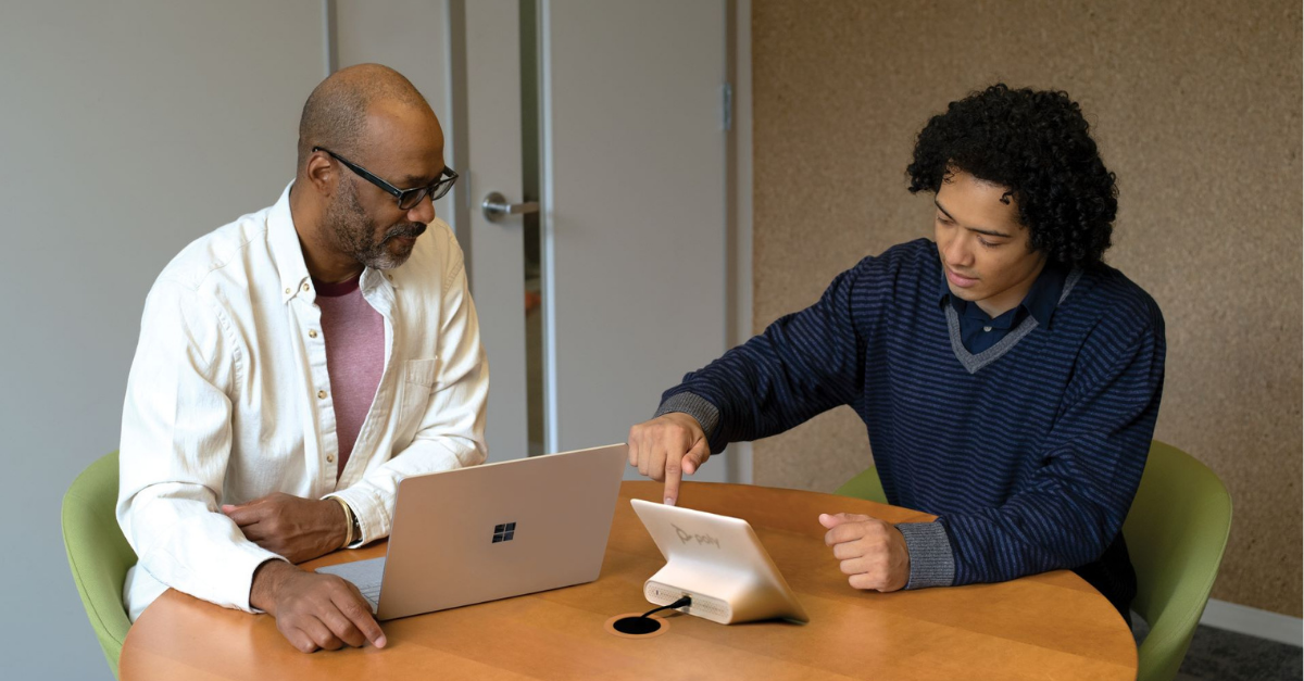 two men having a discussion with one having a laptop in front of him.