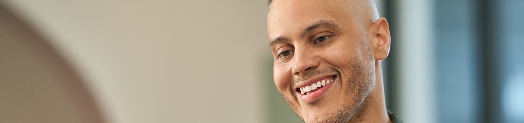 A smiling young man using a laptop.