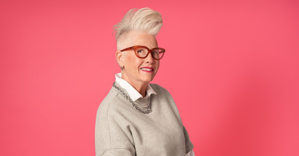 Portrait of a woman in glasses looking at the camera against a bright background.