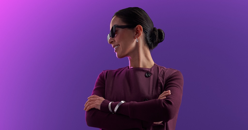 A portrait of a woman wearing sunglasses with arms crossed.