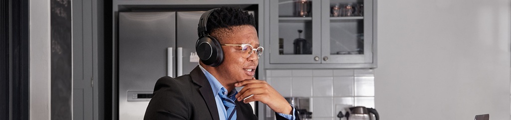 Man in a meeting in front of laptop wearing headphones.