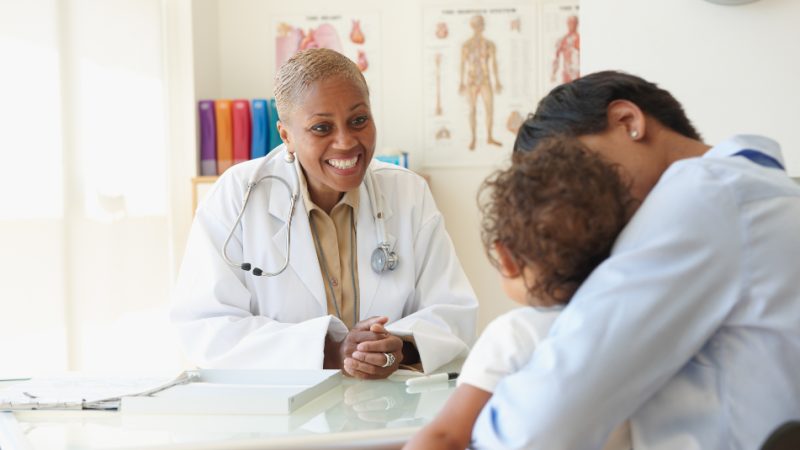 A smiling doctor seeing a young patient.