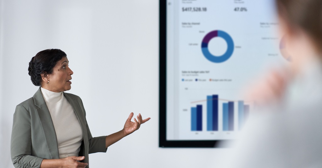 Una mujer de negocios presentando en un gran monitor en una sala de conferencias.