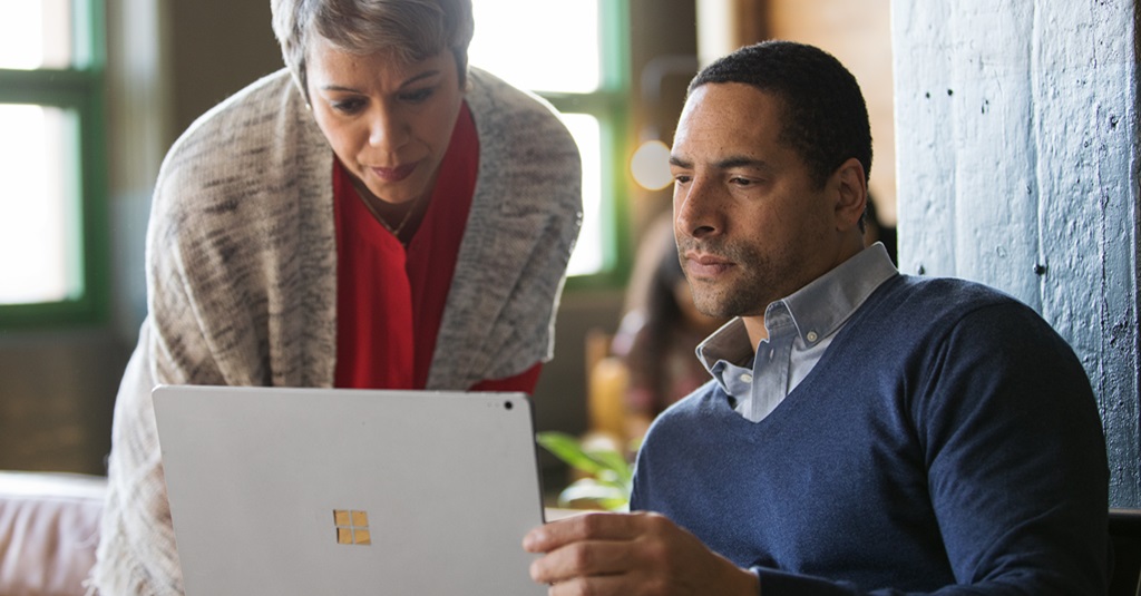 Dos compañeros de trabajo mirando juntos una computadora portátil.