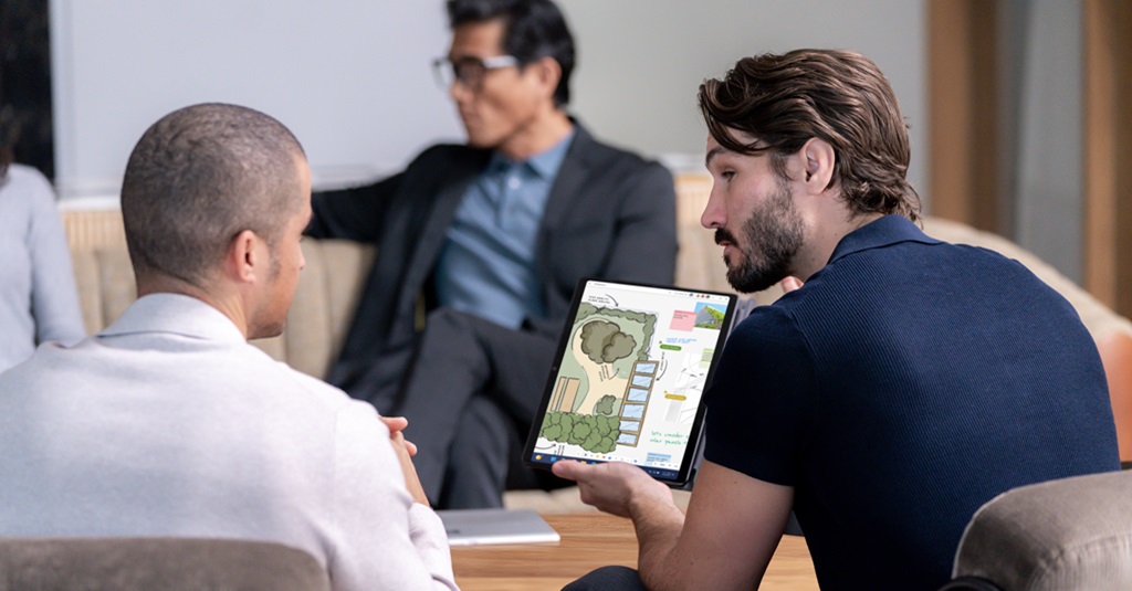Un hombre muestra un plano horizontal en un dispositivo Surface a otra persona.