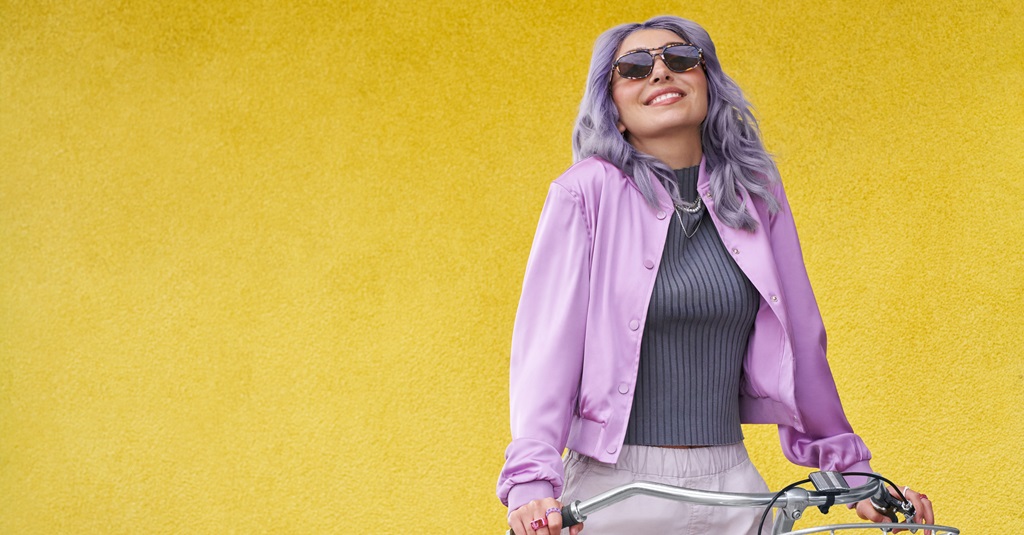 Un retrato de una mujer con gafas de sol sobre un fondo amarillo brillante.