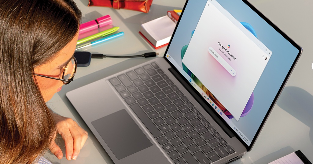 Una mujer joven usando Copilot en su computadora portátil.
