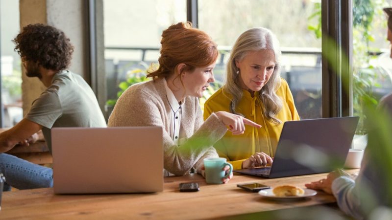 Dos mujeres profesionales mirando juntas una computadora portátil.