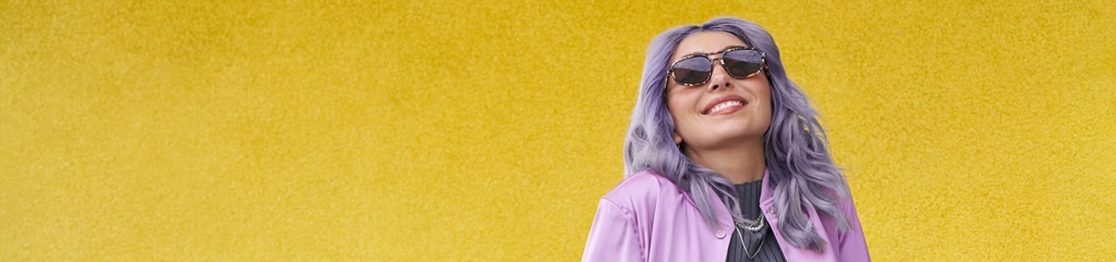Portrait d’une femme en lunettes de soleil sur fond jaune vif.