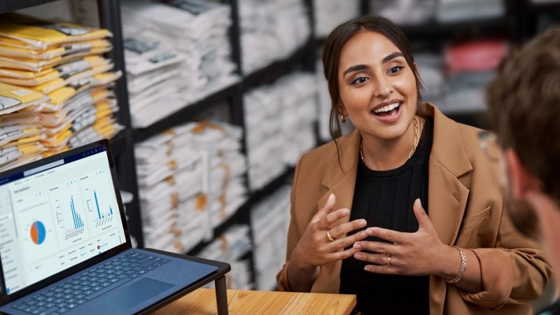 Uma empresária em um armazém conversando com um trabalhador.