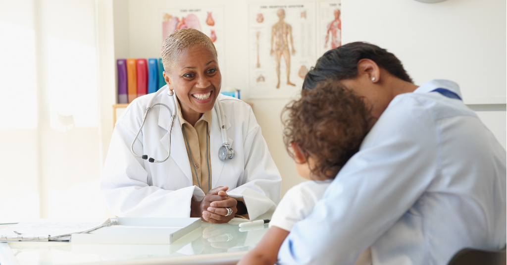 Um médico sorridente atendendo a um jovem paciente.